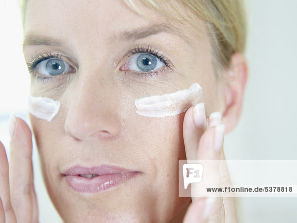 Mature woman applying face cream