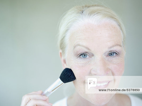 Senior woman applying make up  close up