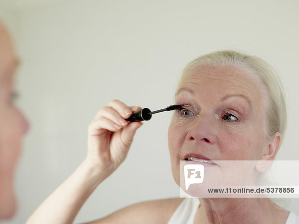 Seniorin beim Augen-Make-up mit Mascara  Nahaufnahme