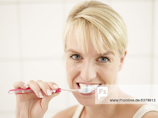 Close up of mature woman doing brushing her teeth  smiling  portrait