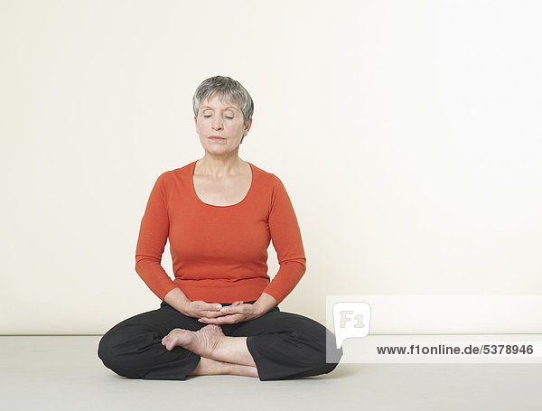 Senior woman doing meditation with eyes closed