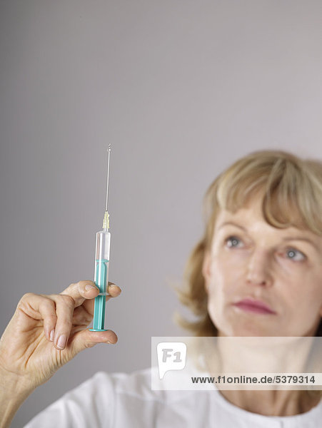 Mature female doctor examining syringe