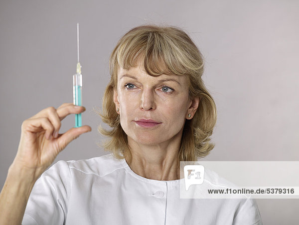 Mature female doctor examining syringe