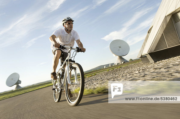 Mature man riding bicycle near radio station