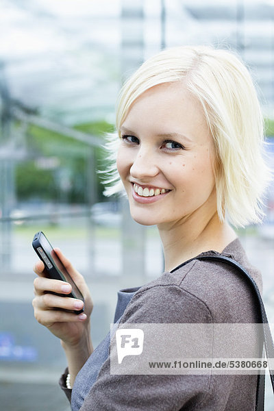 Young woman with cell phone  smiling  portrait