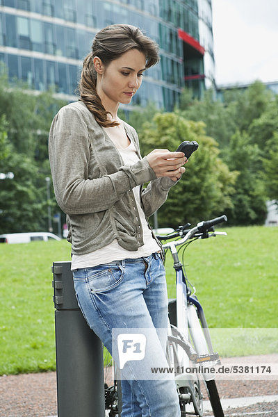 Woman using cell phone besides bicycle