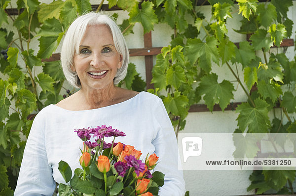 Seniorin mit Blumen  lächelnd  Portrait