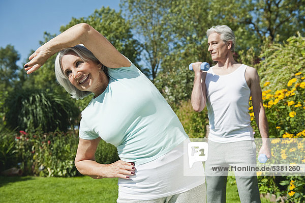 Mature man lifting dumbells  senior woman exercising  smiling
