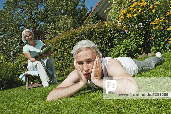 Man tired and woman reading magazine in garden  smiling