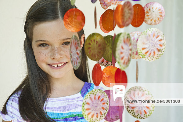 Mädchen mit dekorativen Muscheln Windspiel  lächelnd  Portrait
