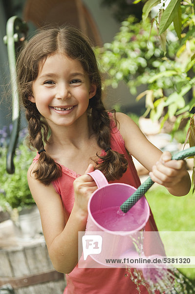 Mädchengartenarbeit mit Gießkanne  lächelnd  Portrait