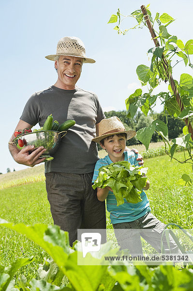 Deutschland,  Bayern,  Großvater mit Enkel im Gemüsegarten,  lächelnd