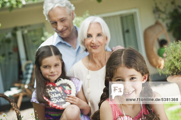 Deutschland  Bayern  Großeltern mit Enkelin  die Lebkuchen hält  lächelnd