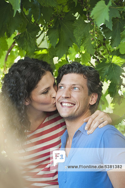 Frau küssend Mann im Garten  lächelnd