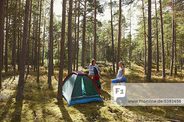 Women setting up campsite in forest