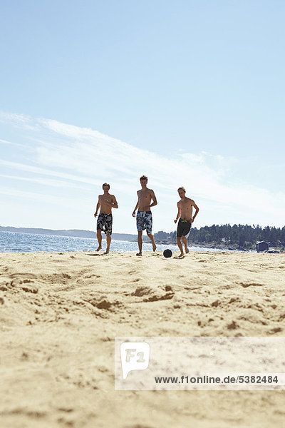 Men playing soccer on beach