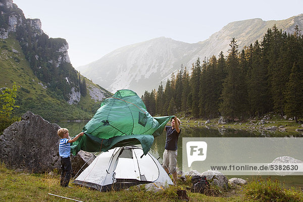 Father and son pitching a tent by lake