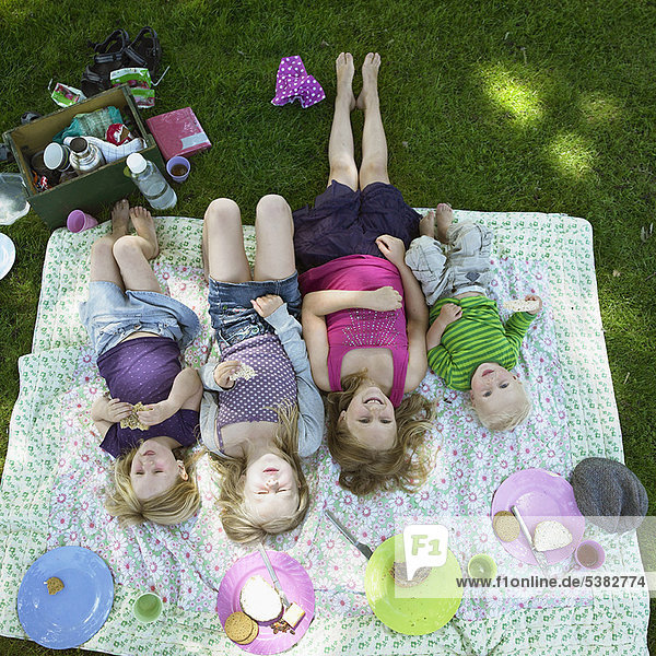 Kinder liegen auf Picknickdecke