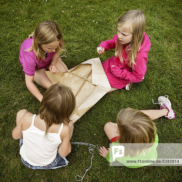 Mädchen beim Drachenbau im Gras