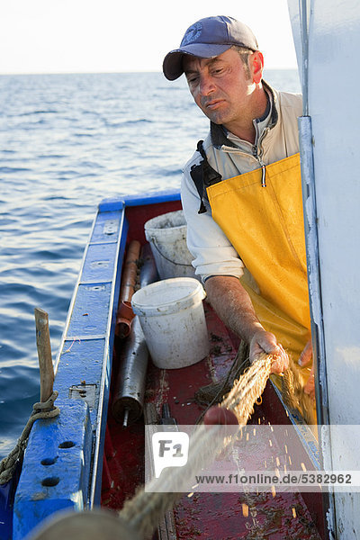 Fisherman reeling in nets on boat