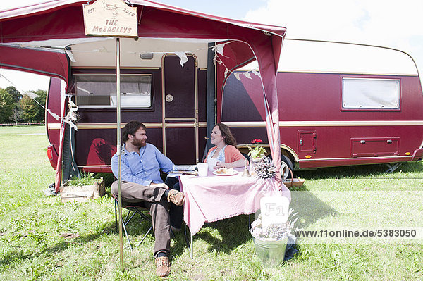 Couple picnicking outside trailer