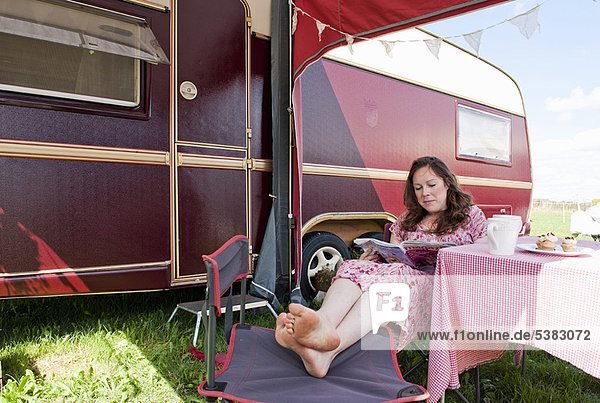 Woman reading magazine outside trailer
