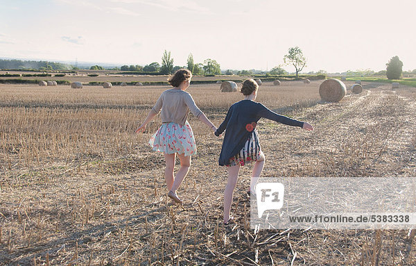 Girls running in hay field