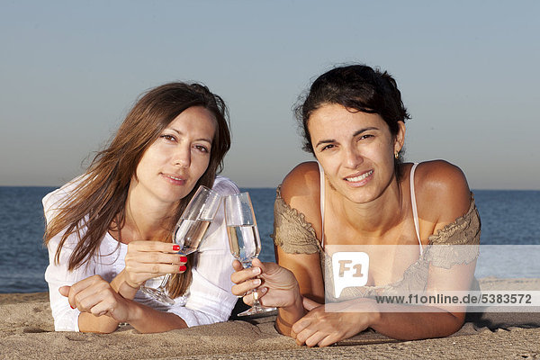 Zwei junge Frauen trinken Sekt am Strand