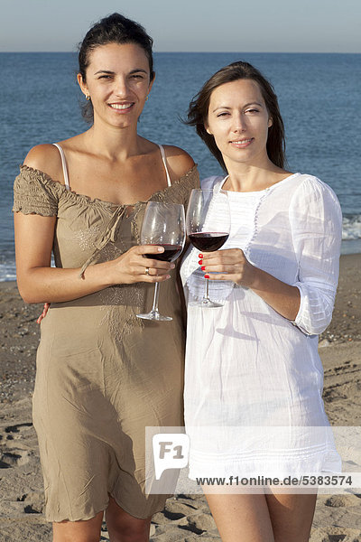 Zwei junge Frauen trinken Wein am Strand