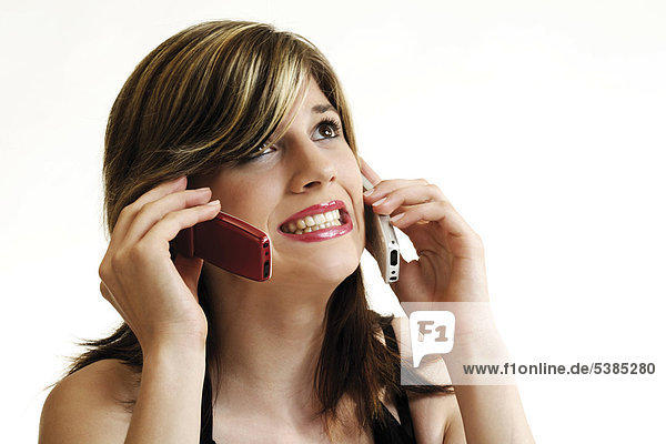 Symbol for mobile phone stress - young woman making phone calls with two mobile phones