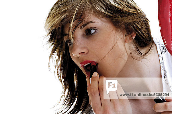 Young woman putting lipstick on