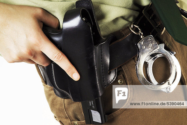 Detailaufnahme: Polizistin mit Pistolenhalfter und Handschellen