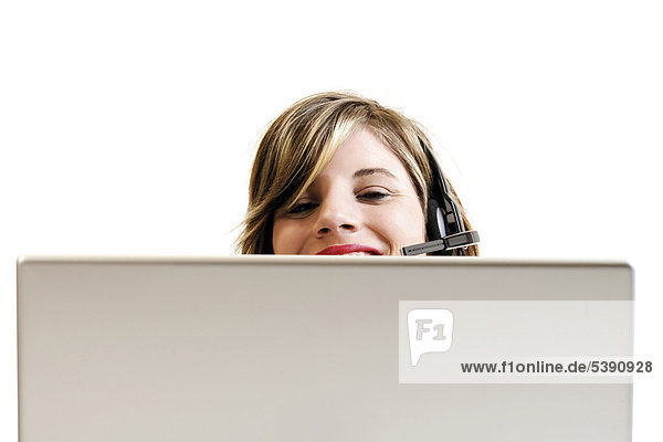 Junge Frau mit Headset hinter einem Laptop - Callcenter