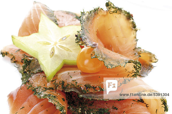 Sliced salmon (gravlax) garnished with starfruit and groundcherries (Physalis)