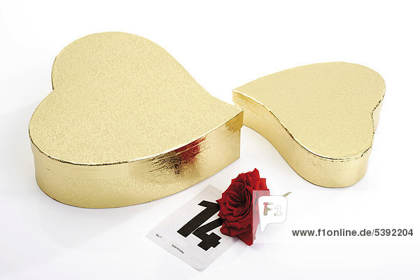 Goldene Geschenkpäckchen in Herzform mit roter Rose und Kalenderblatt 14. Februar - Valentinstag