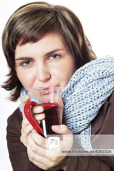 Junge Frau mit Schal trinkt Erkältungstee - Symbolbild für Erkältung