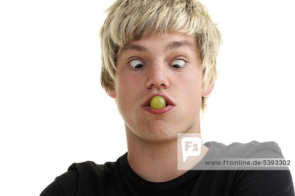 Young man with a grape in his mouth  his eyes crossed