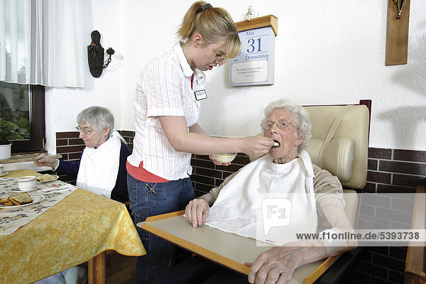 Im Altenheim  Pflegeheim  Pflegerin hilft einer Seniorin beim Essen