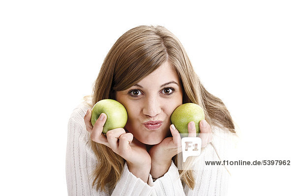 Junge Frau im weißen Rollkragenpullover hält grüne Äpfel