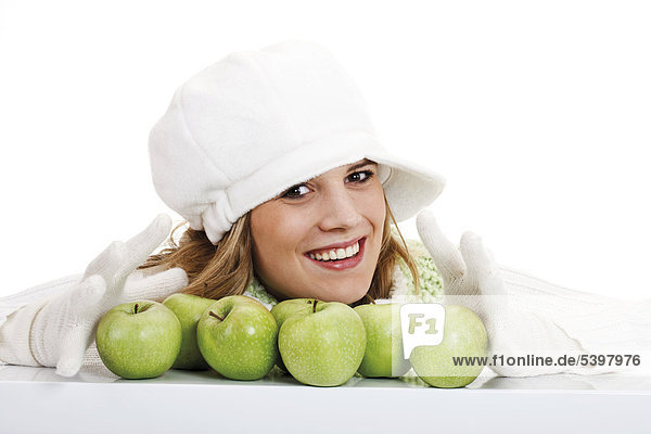 Young woman in a white turtleneck sweater with woolen hat  green apples in front