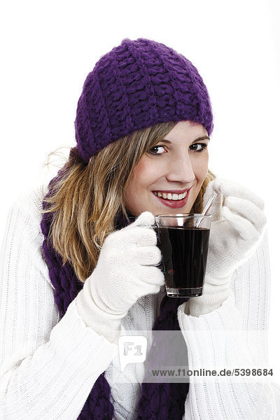 Young woman wearing a purple woolen cap and scarf drinking mulled wine  Gluehwein