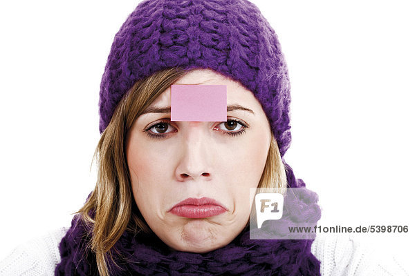 Young woman wearing a purple woolen cap and scarf with a post-it note on her forehead