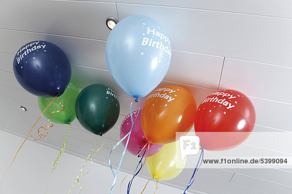 Luftballons Happy Birthday mit Helium gefüllt unter der Zimmerdecke