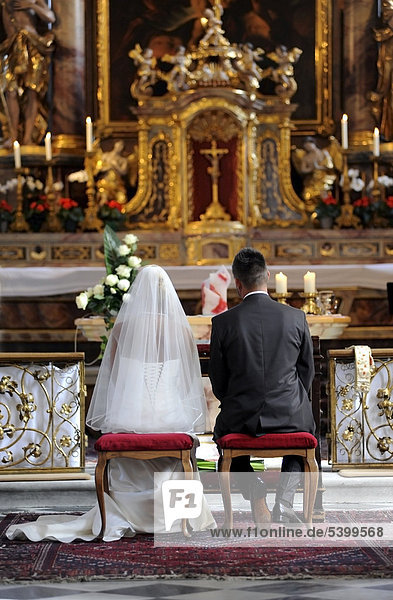 Wedding in church  bride and groom sitting in front of the altar