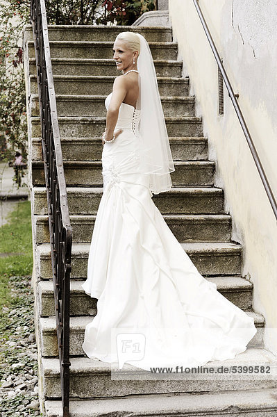 Hochzeit  lächelnde Braut steht auf einer Treppe