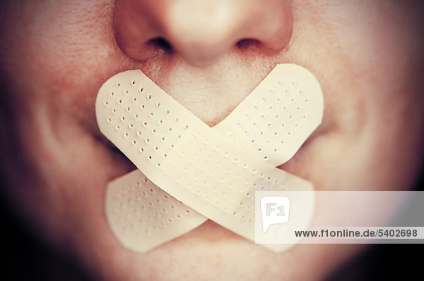 Frau mit Pflaster auf dem Mund  Symbolbild Redeverbot
