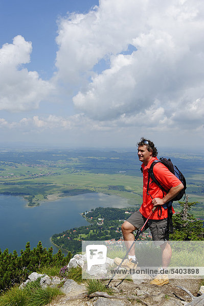 Mountaineer standing on the summit of Sonnenspitz mountain  view of Lake Kochel near Kochel  Upper Bavaria  Bavaria  Germany  Europe