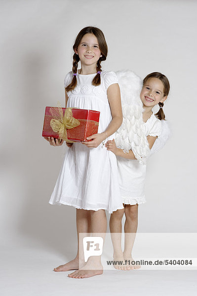 Two girls dressed up as Christmas angels  with a gift  Christmas