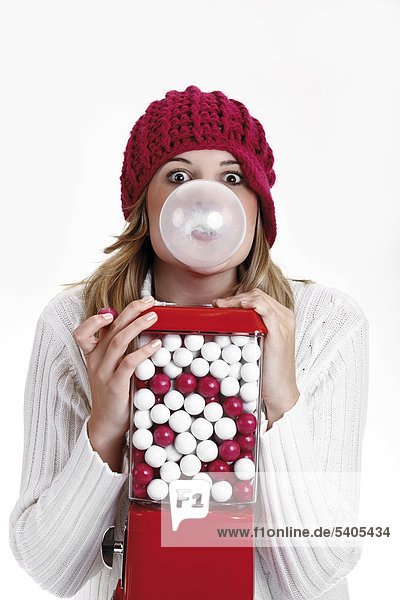 Young woman chewing gum  next to a gumball machine