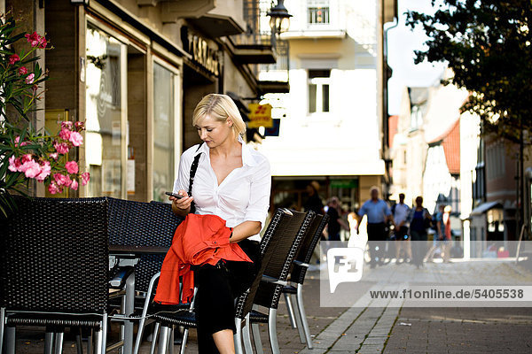 Junge Frau sitzt in einem Straßencafe